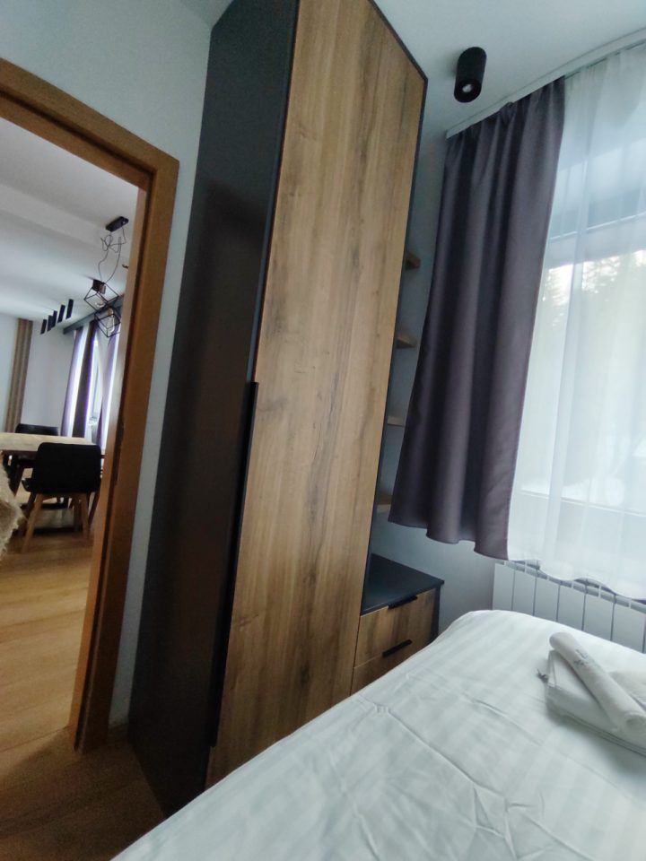 Spavaća soba sa visokim ormarom i prozorom